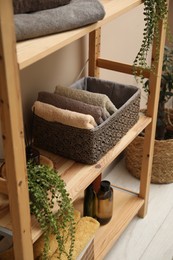 Photo of Soft towels in storage boxes, plant and bottles on shelves indoors