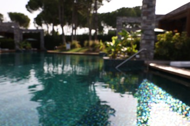 Photo of Blurred view of swimming pool, metal rail and tropical plants at luxury resort