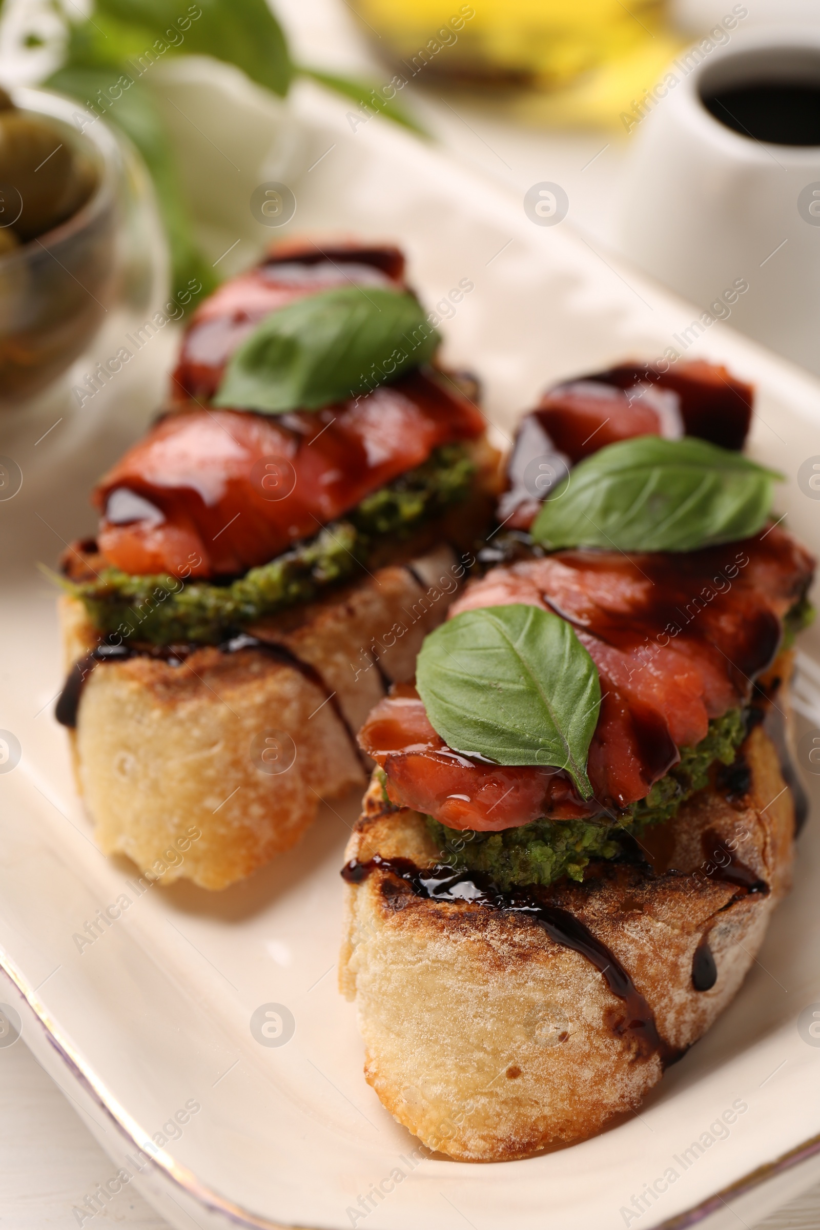 Photo of Delicious bruschettas with balsamic vinegar and toppings on white table, closeup