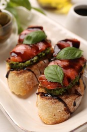 Delicious bruschettas with balsamic vinegar and toppings on white table, closeup