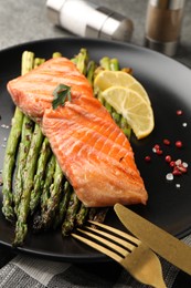 Photo of Tasty grilled salmon with asparagus, lemon and spices served on table, closeup