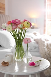 Photo of Beautiful ranunculus flowers on table in bedroom