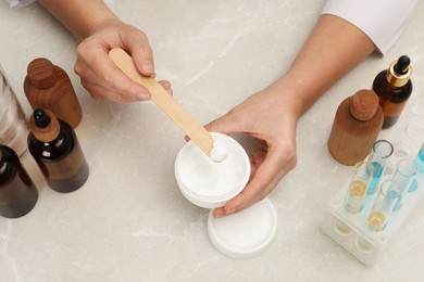 Photo of Dermatologist developing cosmetic product at light marble table, top view