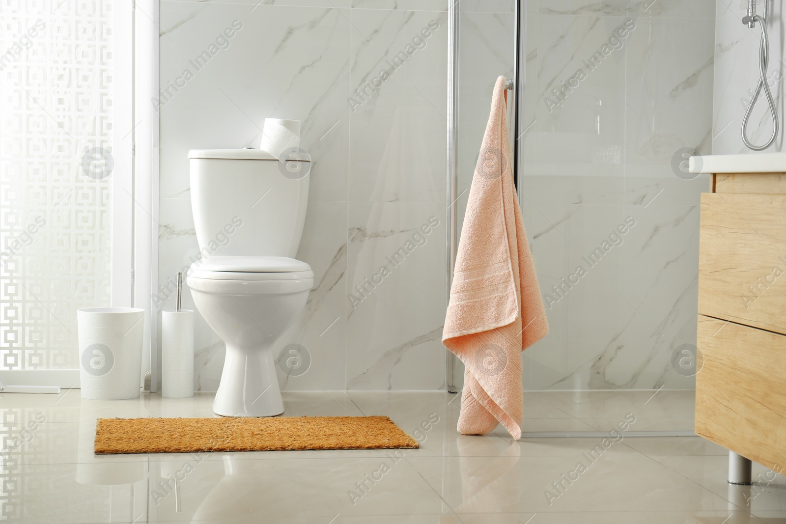 Photo of Toilet bowl near shower stall in modern bathroom interior