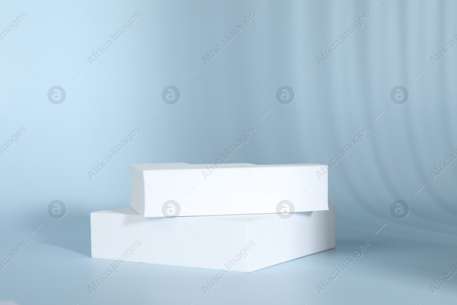 Photo of Presentation of product. White podiums on light blue background. Space for text