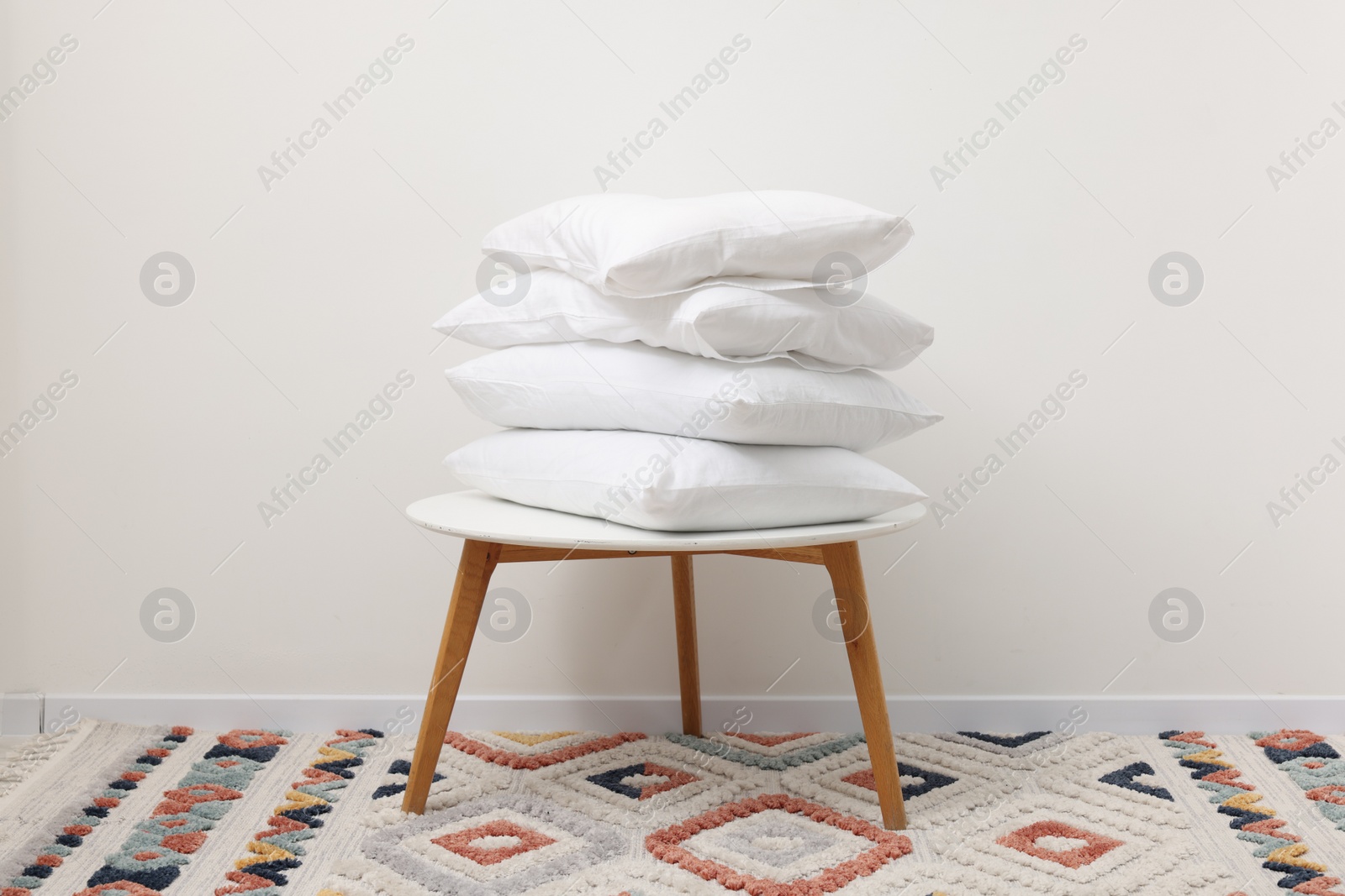 Photo of Soft pillows on side table near light wall indoors