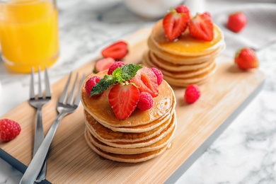 Photo of Tasty pancakes with berries on wooden board