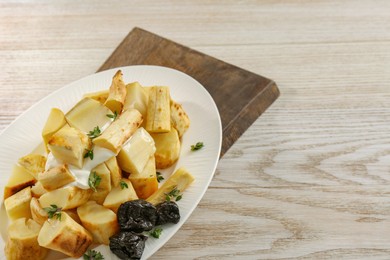 Photo of Tasty homemade parsnips with prunes and thyme on white wooden table, closeup. Space for text