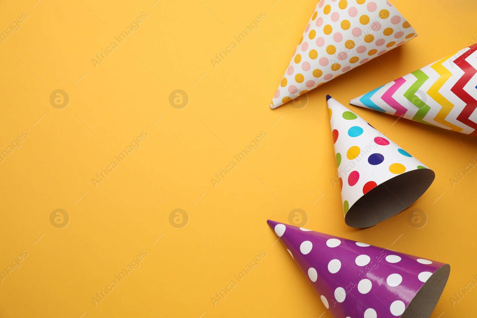 Photo of Bright party hats on orange background, flat lay. Space for text