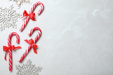 Sweet Christmas candy canes and snowflakes on grey background, flat lay. Space for text