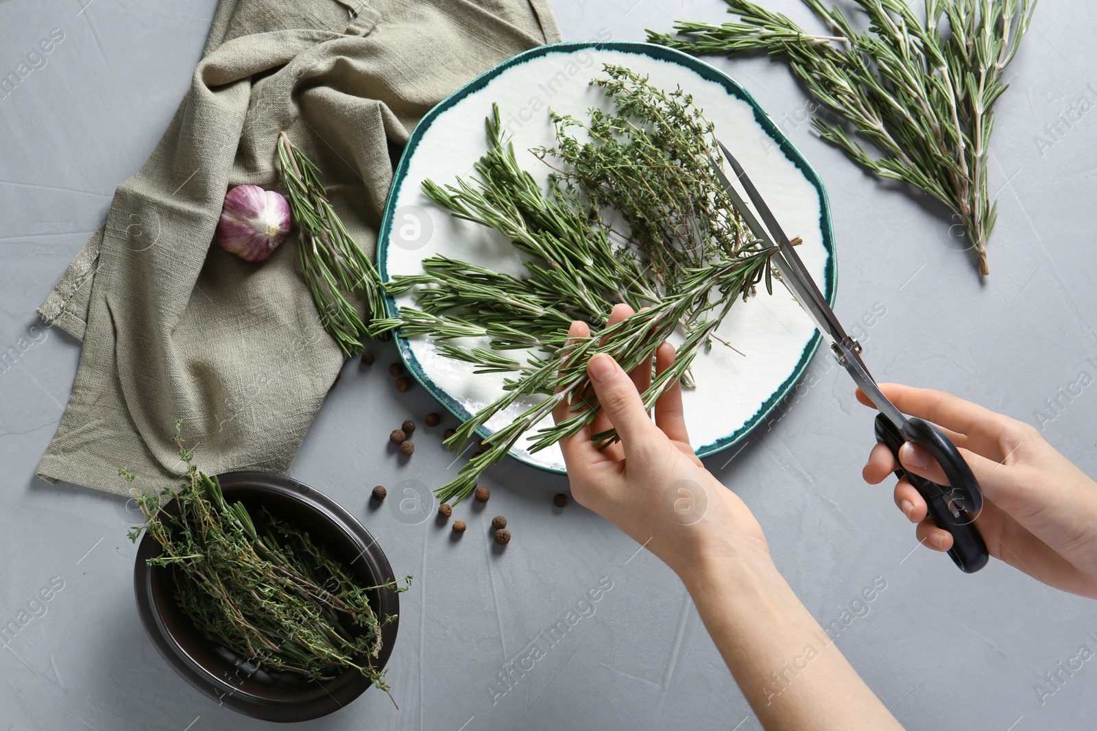 Photo of Woman cutting fresh rosemary over table, top view. Aromatic herbs