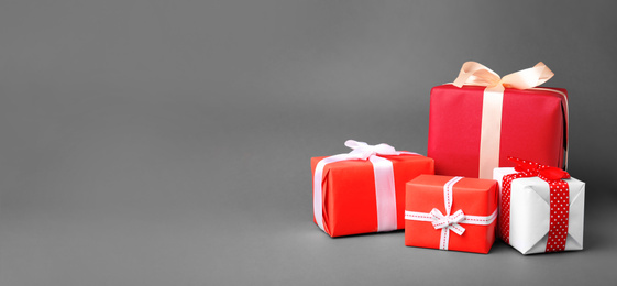 Image of Beautiful gift boxes with ribbons and space for text on grey background. Banner design