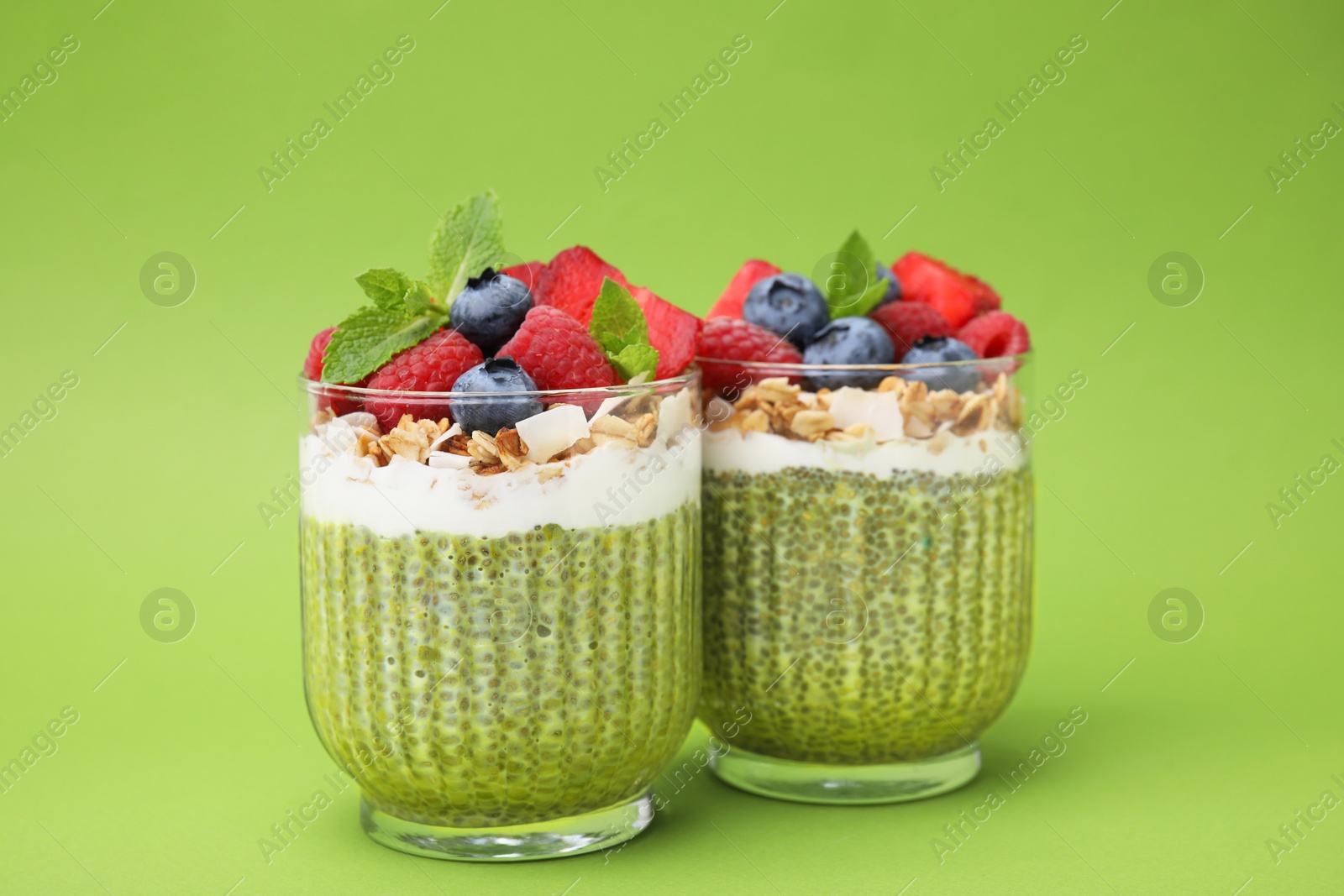 Photo of Tasty matcha chia pudding with oatmeal and berries on green background. Healthy breakfast