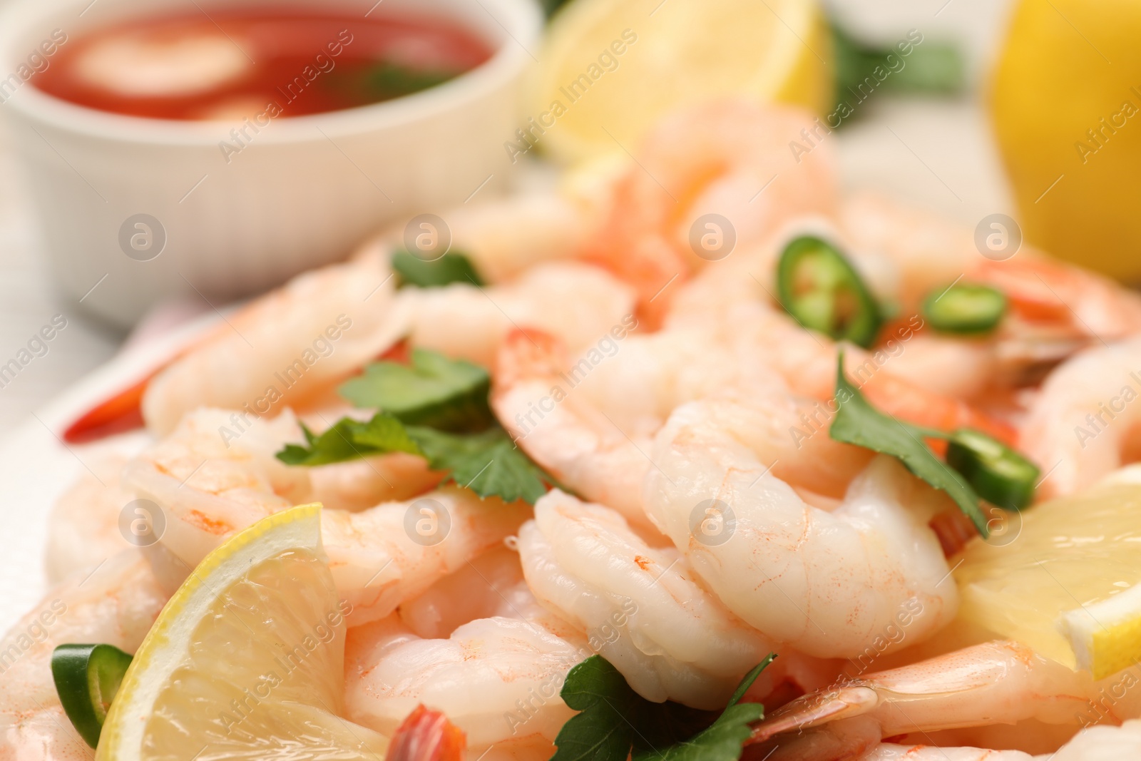 Photo of Tasty boiled shrimps with cocktail sauce, chili and parsley on table, closeup