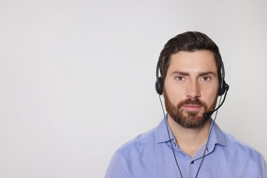 Photo of Hotline operator with headset on light grey background, space for text