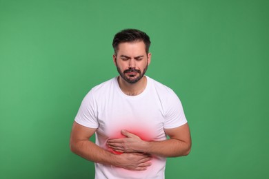 Man suffering from stomach pain on green background