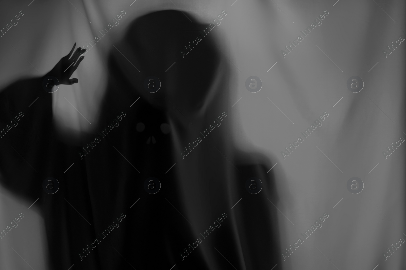 Photo of Silhouette of creepy ghost behind grey cloth, space for text