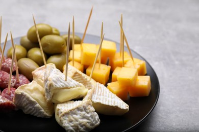 Photo of Toothpick appetizers. Pieces of cheese, sausage and olives on light grey table, closeup. Space for text