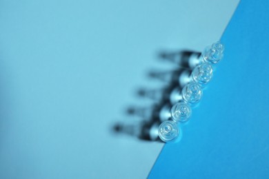 Photo of Pharmaceutical ampoules with medication on blue background, flat lay. Space for text