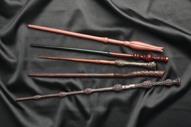 Photo of Different magic wands on black fabric, flat lay