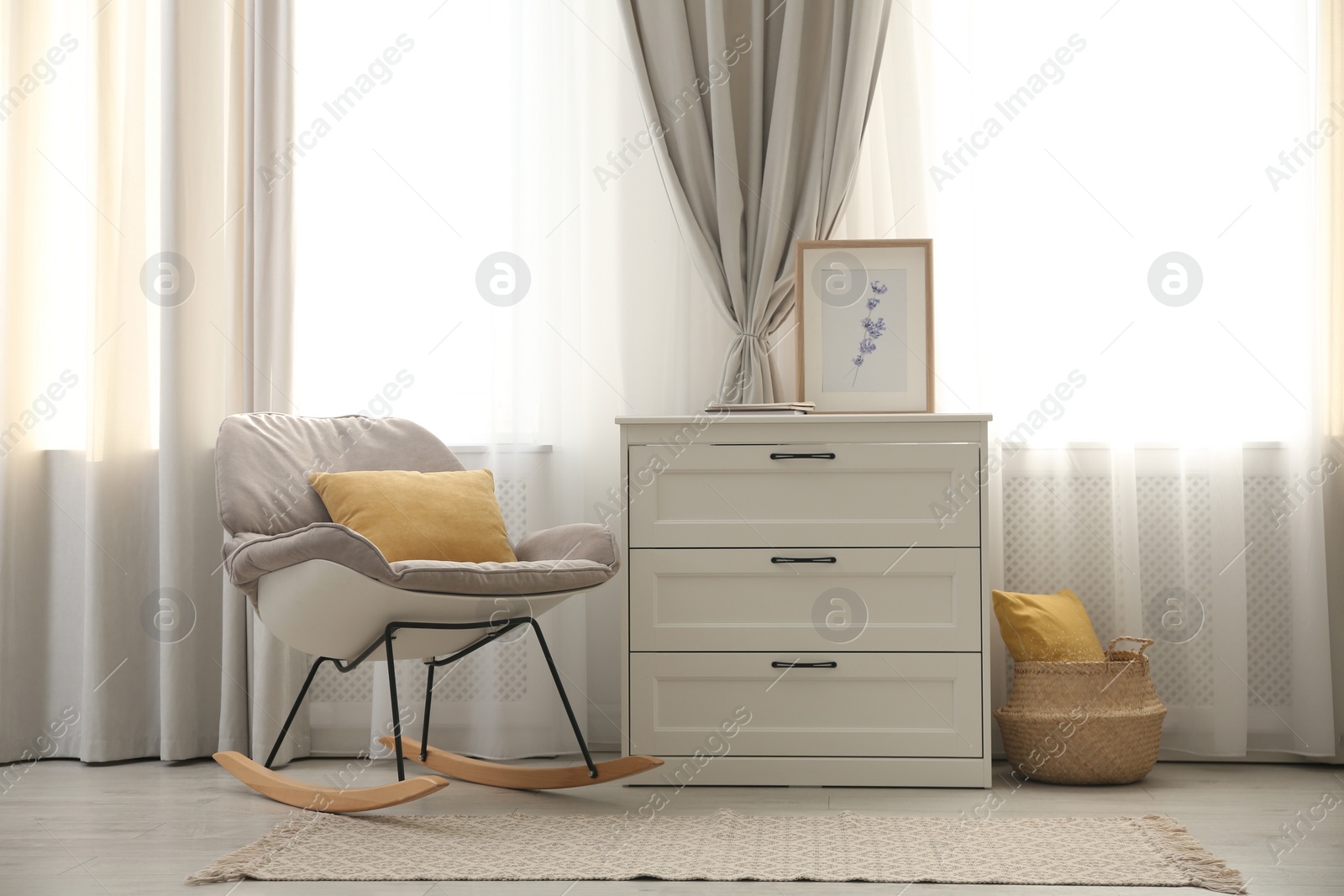 Photo of Rocking chair and chest of drawers near window with stylish curtains in living room. Interior design