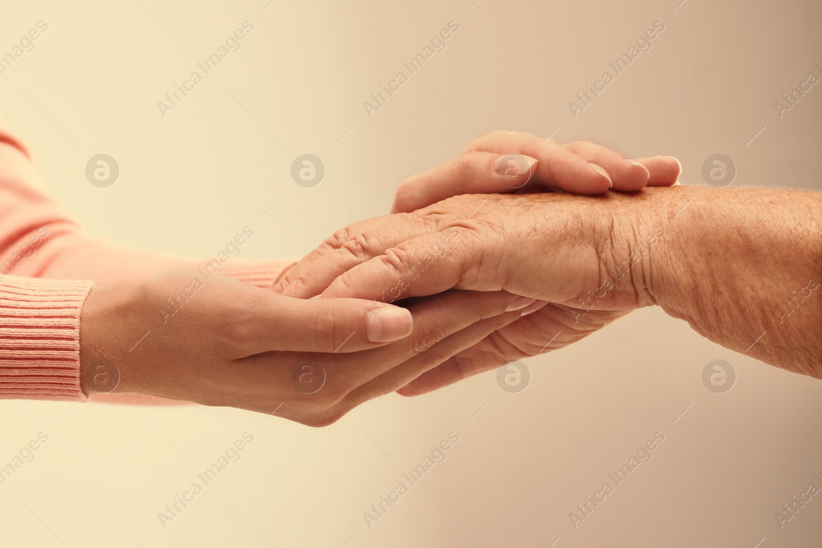 Image of Helping hands on light background, closeup. Elderly care concept