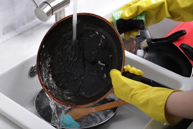 Woman washing frying pan in kitchen sink, closeup