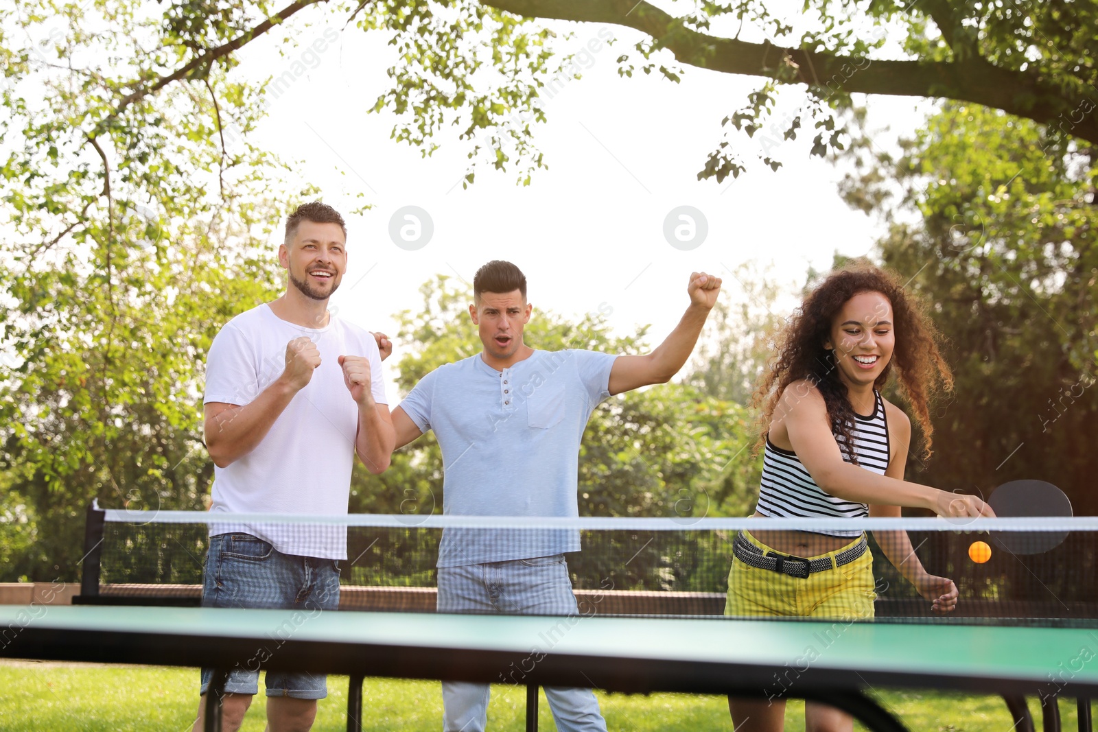 Photo of Friends playing ping pong outdoors on summer day