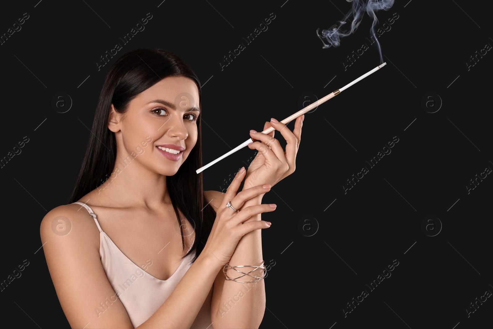 Photo of Woman using long cigarette holder for smoking on black background, space for text