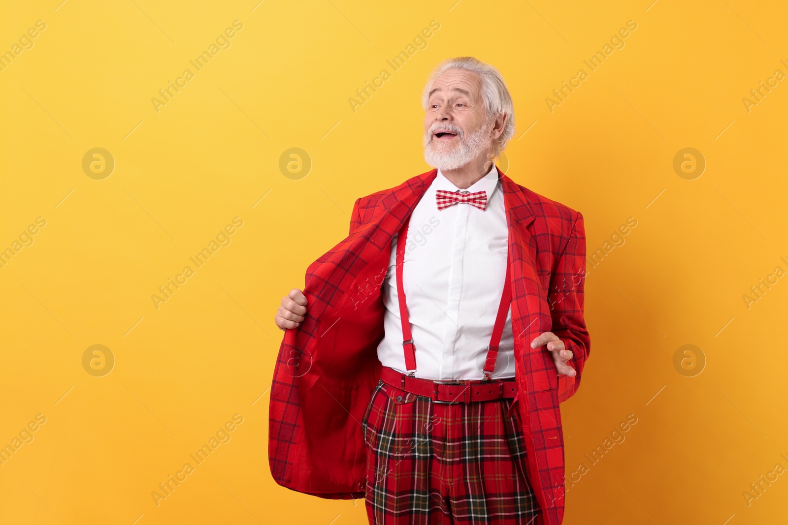 Photo of Portrait of grandpa with stylish red suit and bowtie on yellow background, space for text