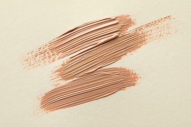 Photo of Samples of liquid skin foundations on beige background, top view
