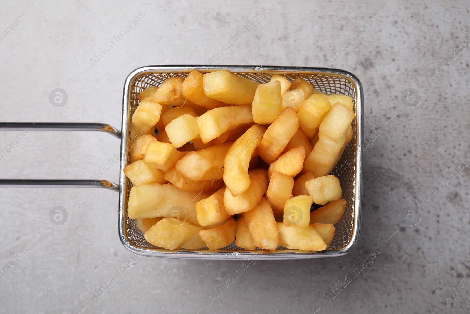 Photo of Frying basket with tasty french fries on light grey table, top view