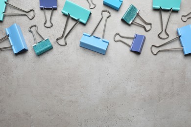 Colorful binder clips on grey stone table, flat lay. Space for text