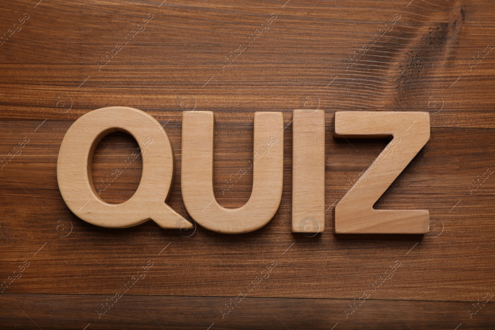 Photo of Word Quiz made with letters on wooden table, flat lay