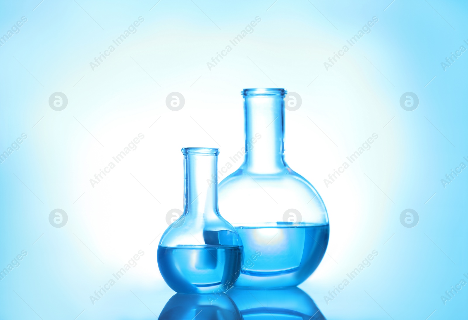 Photo of Laboratory glassware with liquid on color background. Solution chemistry