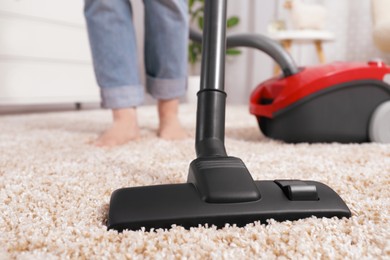 Photo of Woman cleaning carpet with vacuum cleaner at home, closeup