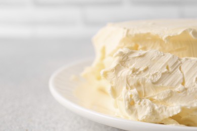Photo of Plate with tasty homemade butter on white textured table, closeup. Space for text