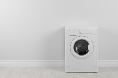 Photo of Modern washing machine near white wall, space for text. Laundry day