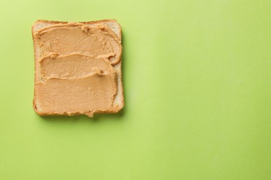 Photo of Tasty peanut butter sandwich on light green background, top view. Space for text