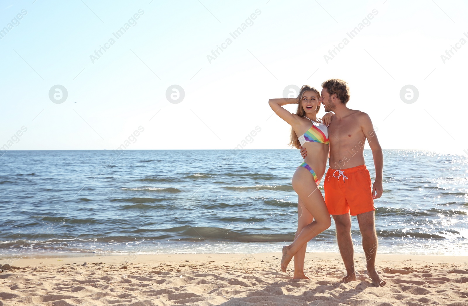 Photo of Happy young couple in beachwear posing on seashore