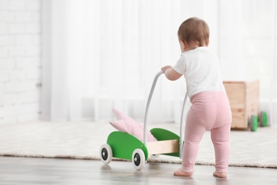 Photo of Cute baby with toy walker at home