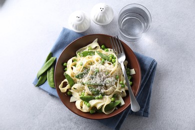 Delicious pasta with green peas and cheese served on grey table