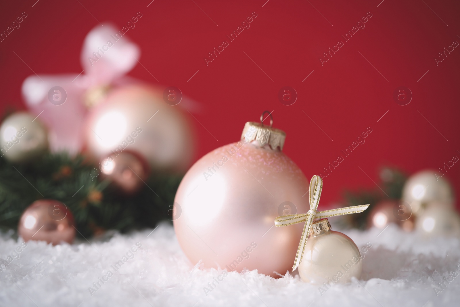 Photo of Beautiful Christmas balls on snow against red background