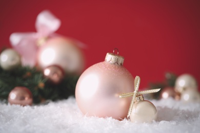Photo of Beautiful Christmas balls on snow against red background