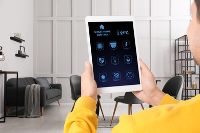 Man using smart home control system via application on tablet indoors, closeup