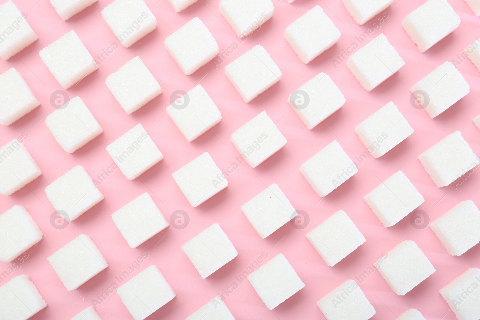 Photo of White sugar cubes on pink background, top view