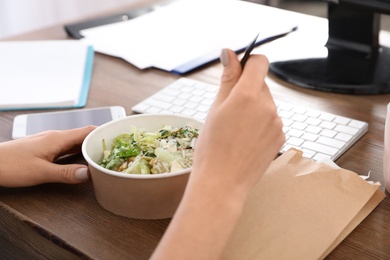 Photo of Office employee having salad for lunch at workplace, closeup. Food delivery