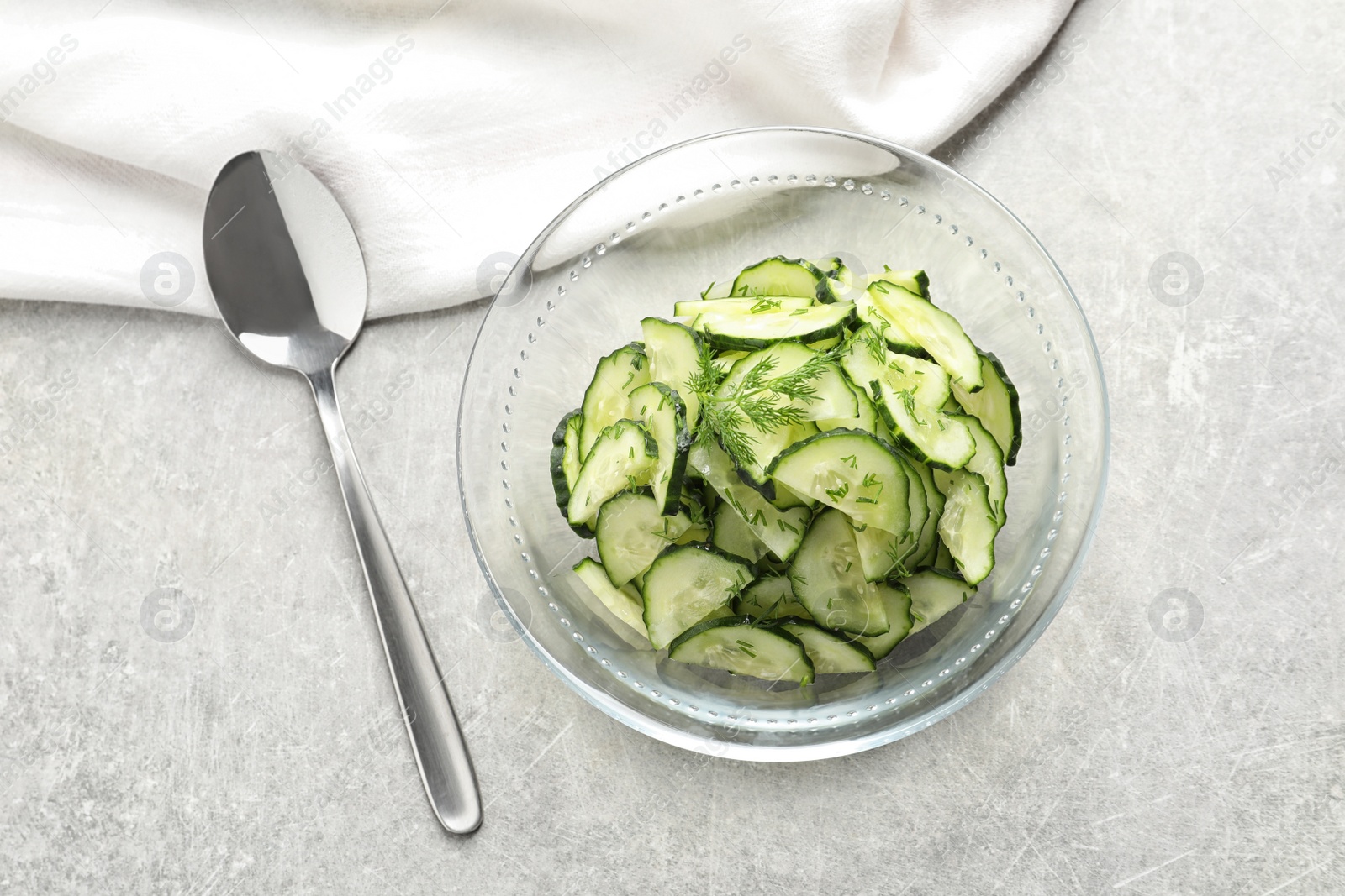 Photo of Delicious cucumber salad with dill in bowl served on grey table, top view