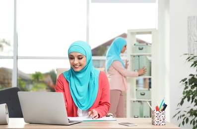 Photo of Modern Muslim women working in light office