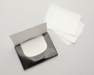 Package with facial oil blotting tissues on light grey background, flat lay. Mattifying wipes